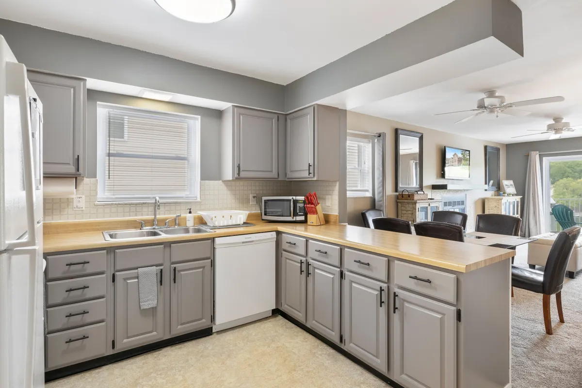 A bright, functional kitchen showcasing modern appliances, ample countertop space, and a window for natural light. The setup is perfect for meal preparation or family gatherings, illustrating the fully stocked essentials mentioned in the section.