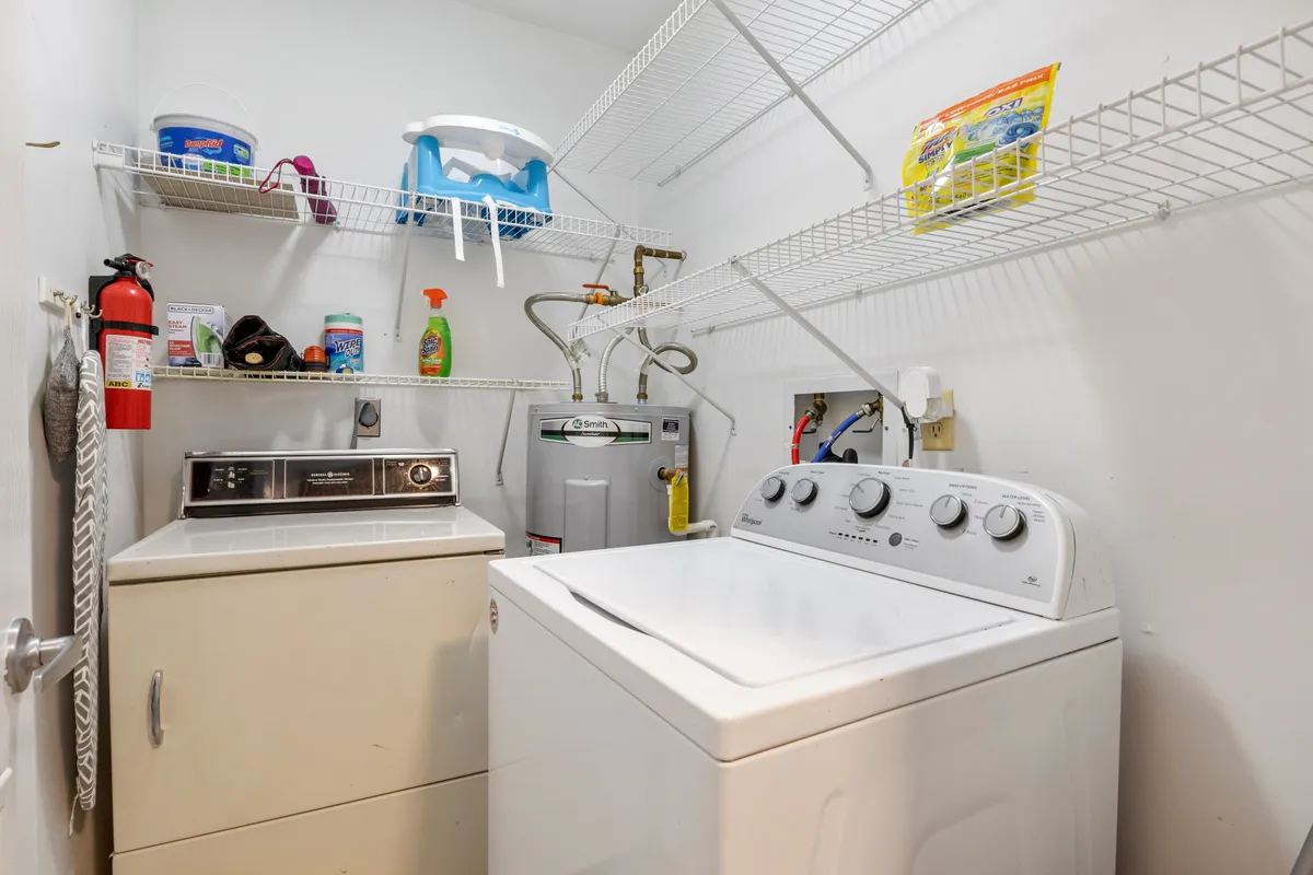 A practical laundry room featuring a washer, dryer, organized shelves lined with cleaning supplies, and a visible fire extinguisher for safety. The design promotes ease and peace of mind for families and organized travelers.