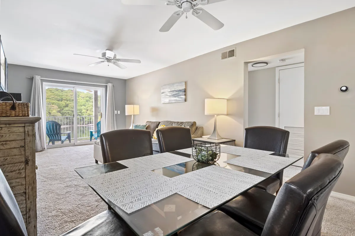 A cozy, open-concept interior featuring a dining table set for family meals, a sofa area for relaxation, and a sliding glass door letting in natural light. Thoughtful artwork on the walls and comfortable furnishings create a welcoming atmosphere ideal for gathering and unwinding.