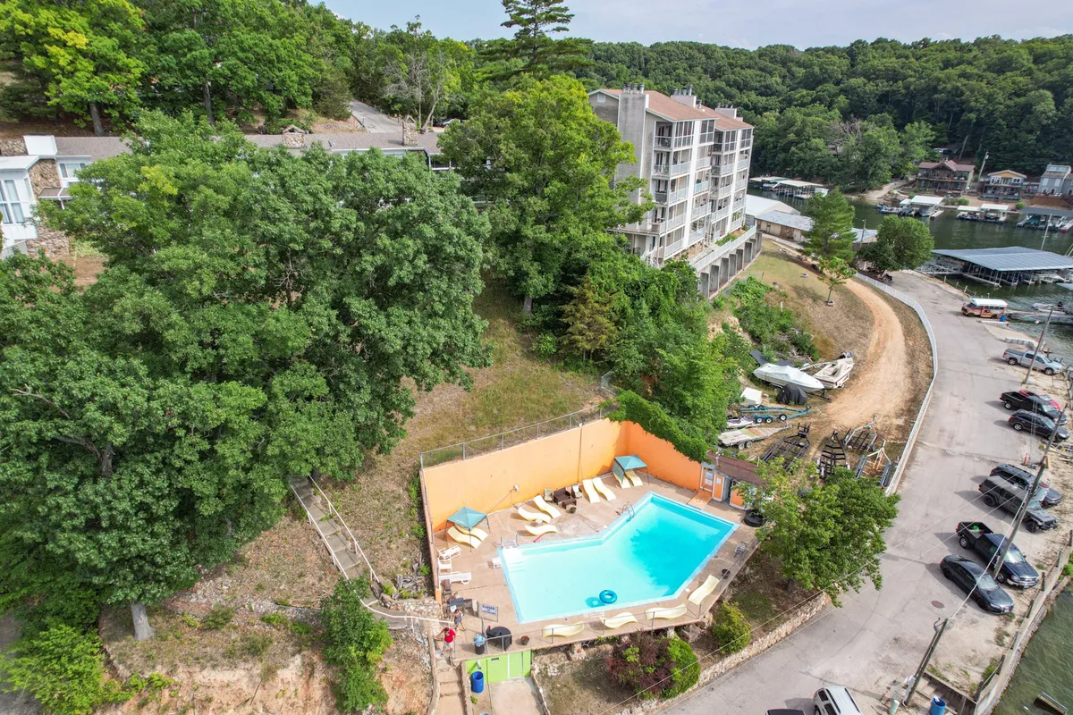 An inviting swimming pool surrounded by lush greenery and the marina, with people lounging and enjoying the water. The hotel building and nearby boats set a relaxed, resort-like tone, perfect for unwinding with friends after a day out.
