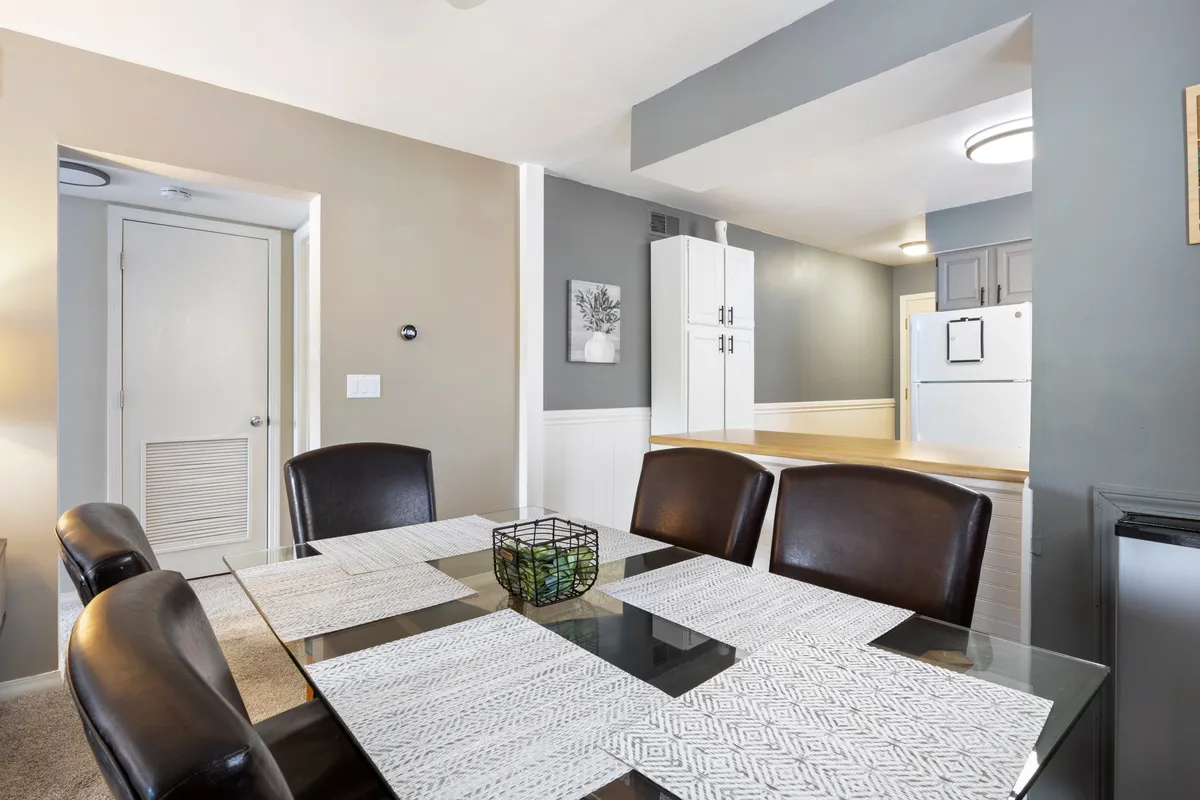 A bright, comfortable dining table stands adjacent to the kitchen area, with stylish wall art and modern accents. The space encourages shared meals, celebrations, and intimate conversations, all while fostering a sense of togetherness.