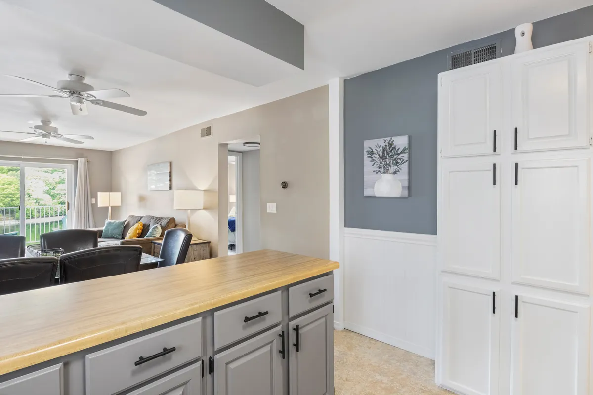 A wide-angle view encompassing the kitchen island and adjacent living area with comfortable seating. Artwork on the wall adds a touch of personality, and the layout emphasizes an easy flow between cooking, relaxing, and socializing.