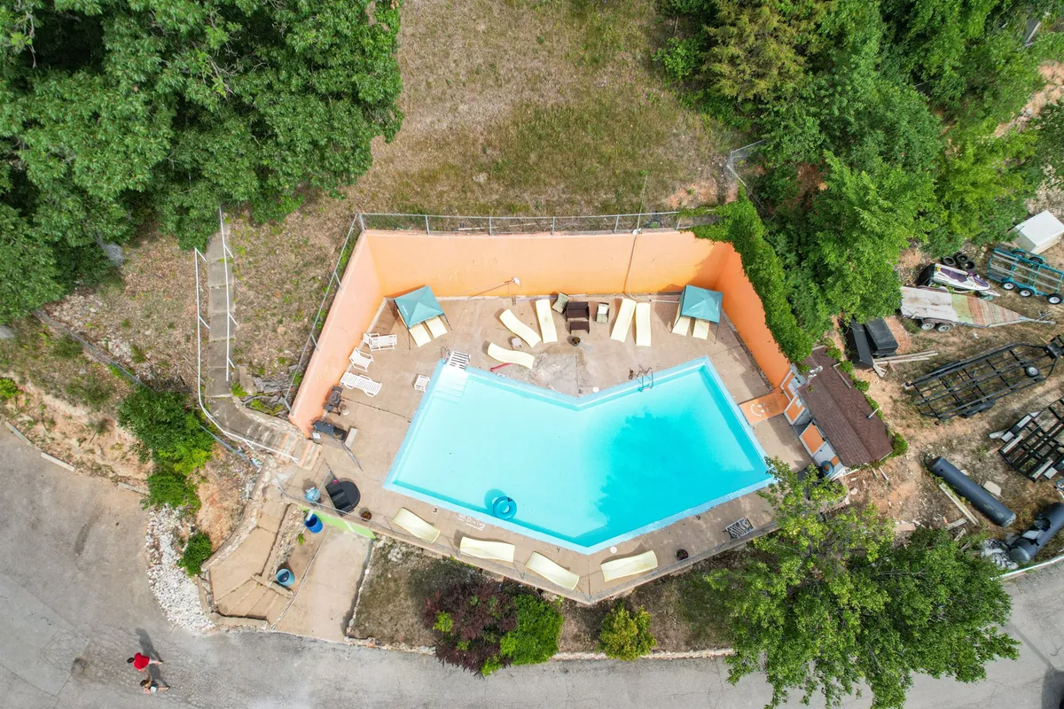 An outdoor pool area surrounded by lounge chairs, lush greenery, and canopies, with children playing and splashing in the water. The atmosphere is leisurely and inviting, ideal for family relaxation after a day of lake adventures.